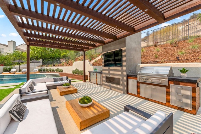 Luxury outdoor kitchen and covered living remodel with grill, sink, storage, and pool area